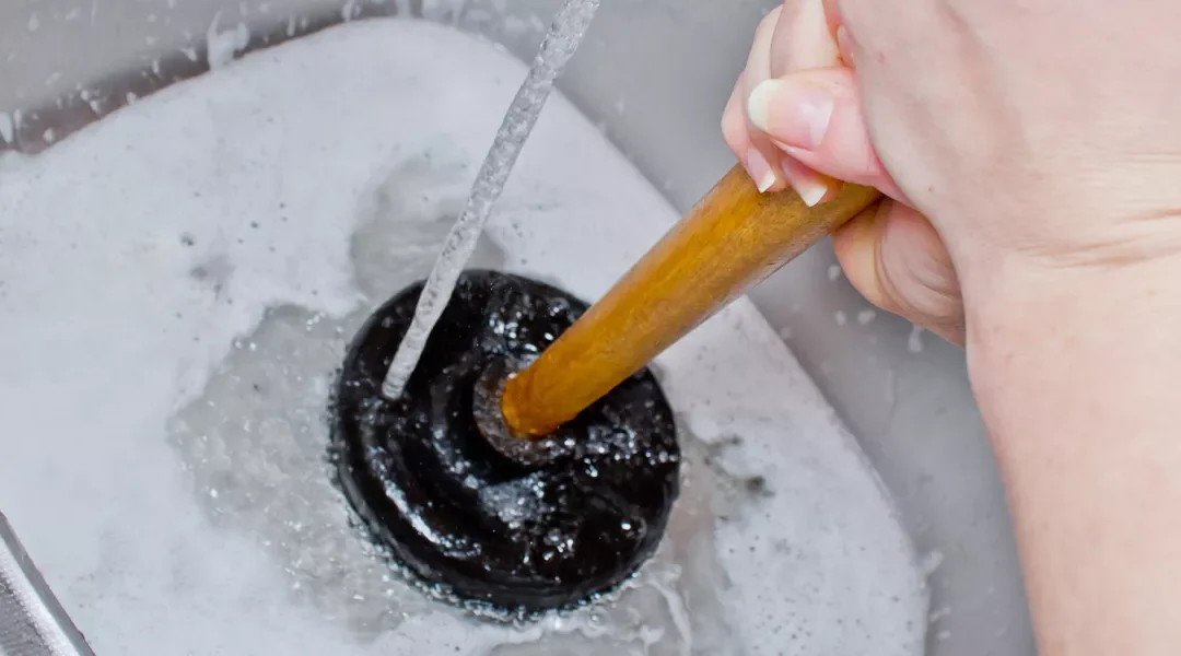 someone using a plunger, how to unclog a drain