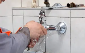 Plumber fixing bathtub faucet that is spraying water