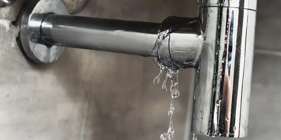 A chrome shower faucet leaking a bunch of water