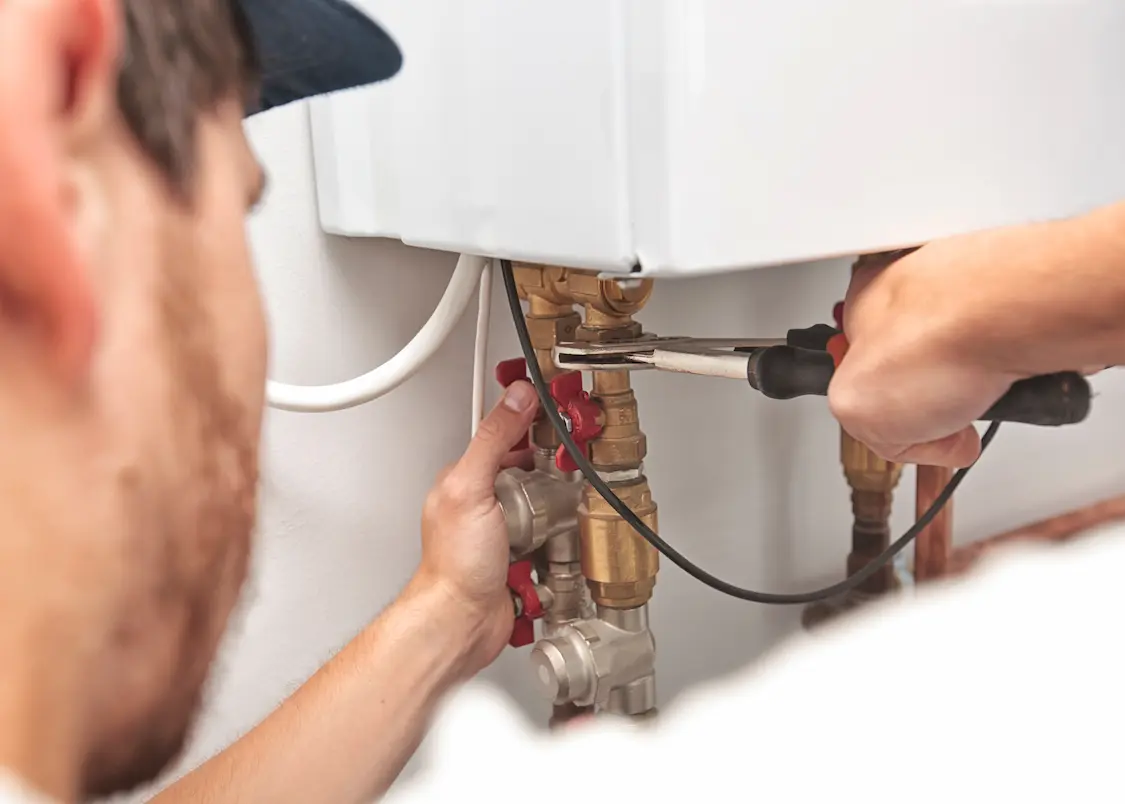 An over-the-shoulder shot of a technician repairing a water heater.