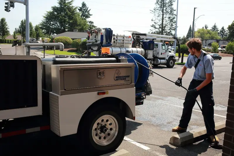 Services-page-drain-cleaning Technician running a hose from a truck into a drain hole